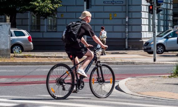 A man biking across a city street intersection on a sunny day. Urban commuting lifestyle.